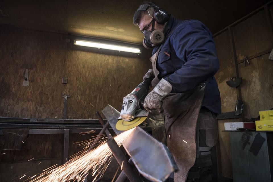 Schruppen von Stahlblech mit Winkelschleifer in einer Werkstatt
