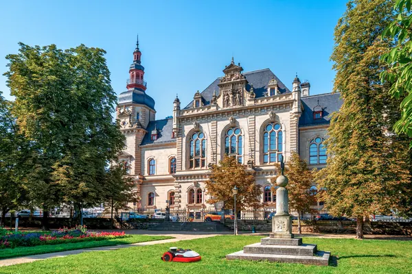 Kress Mähroboter auf der Grünfläche vor einem historischen Rathaus